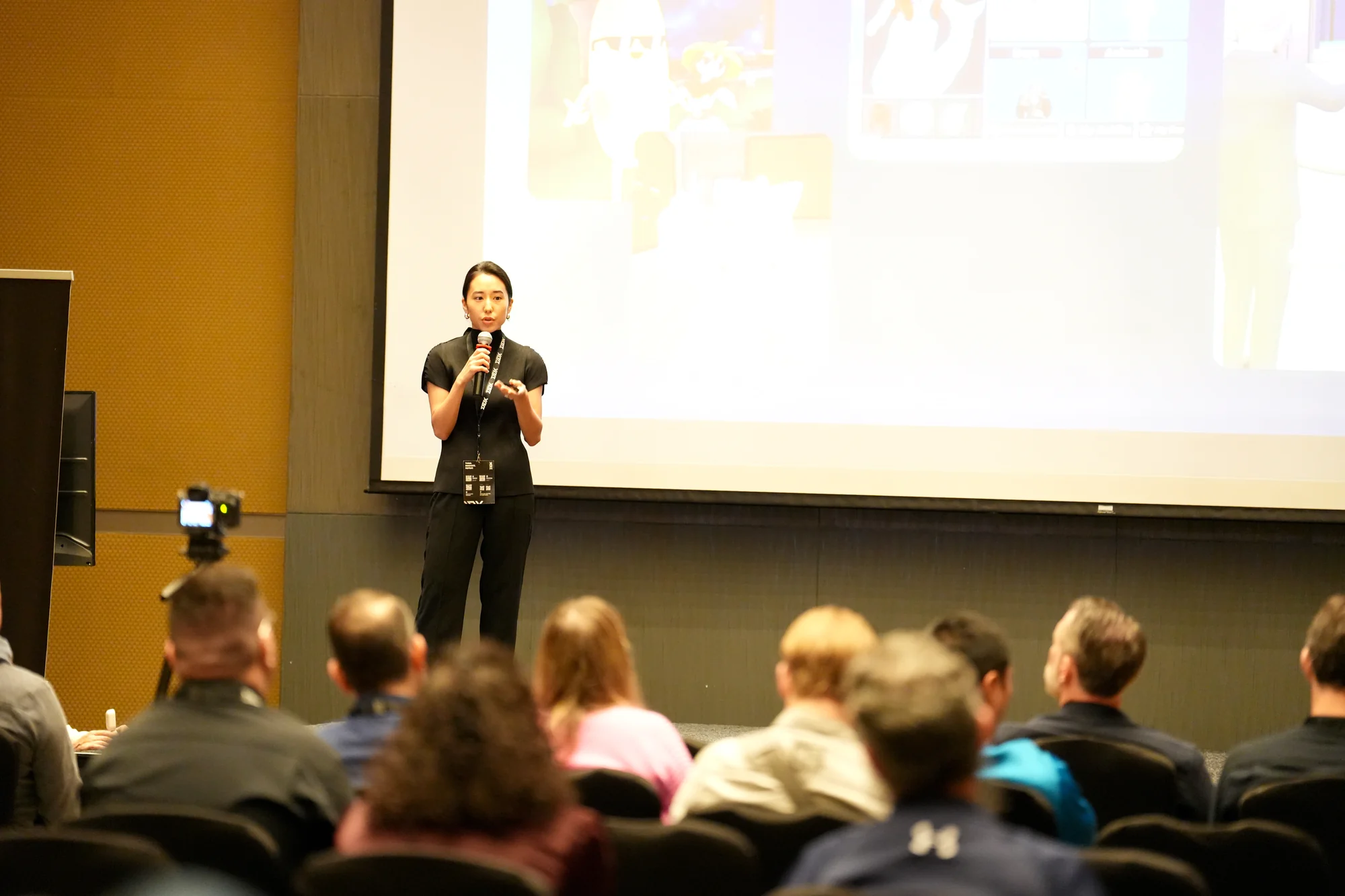 Jasmine Oh presenting solo on stage at DDX, slides projected behind her