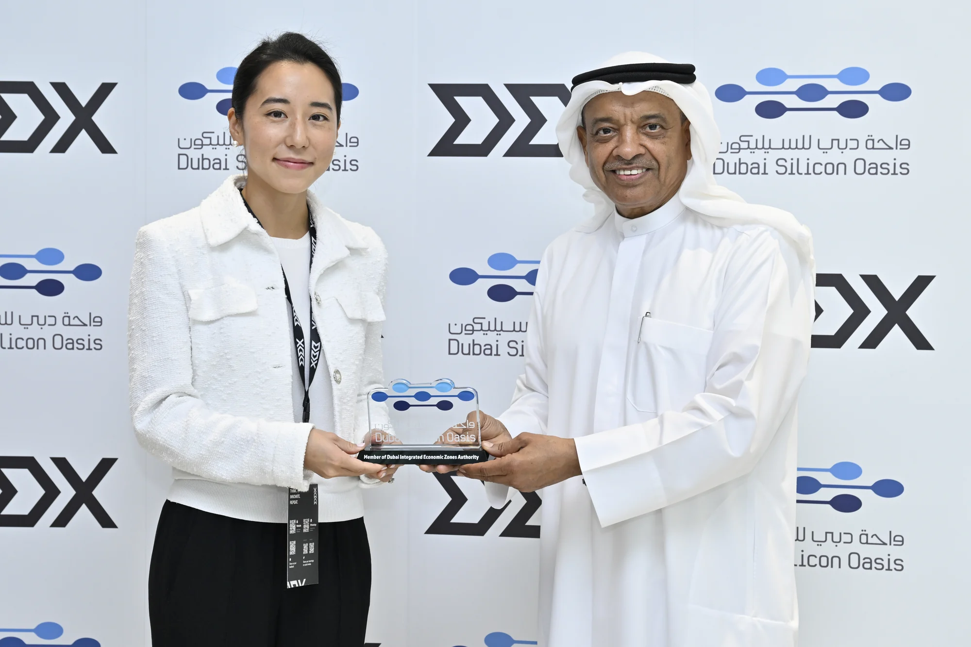 Jasmine Oh receiving an award at the Dubai Silicon Oasis backdrop